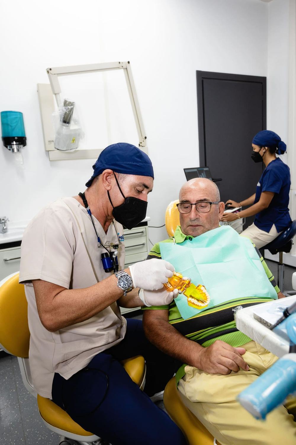 Il Dott. Roberto Foli e un'assistente durante una cura, con il paziente sulla poltrona